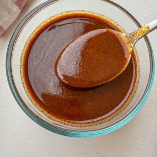 Quick and easy homemade red enchilada sauce in a glass bowl with a spoon.