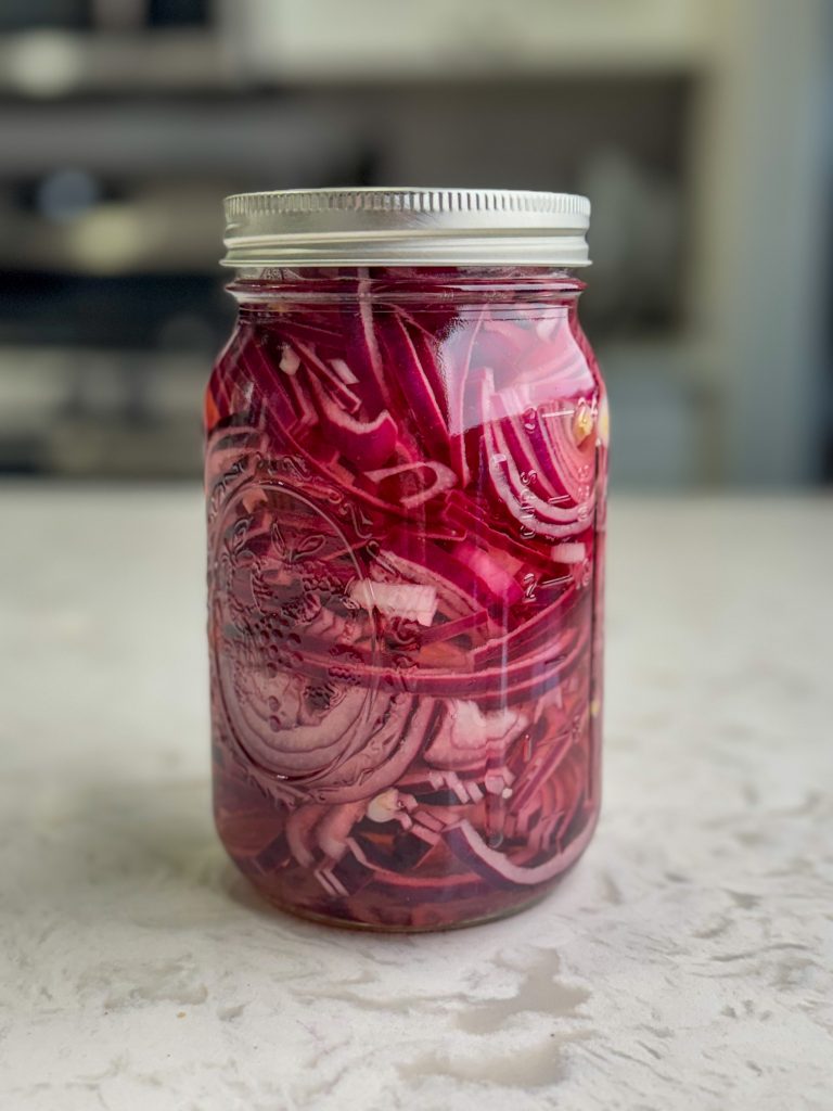 Quick and easy pickled red onions in a large mason jar.