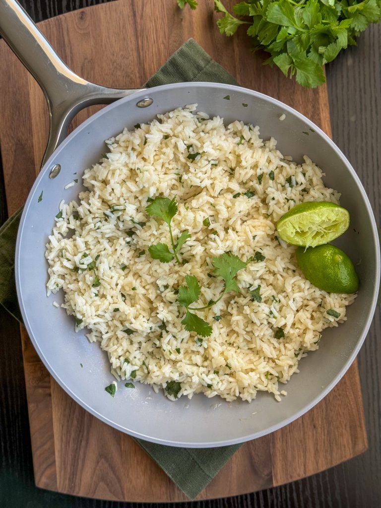 Quick and easy cilantro lime rice in a pan with squeezed limes and fresh cilantro.