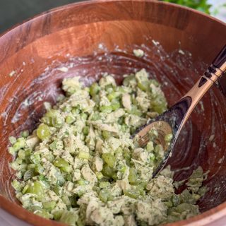 Large wooden bowl of herby green goddess chicken salad with wooden spoon.