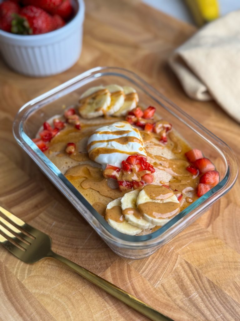 Microwave pancake bowl with greek yogurt, peanut butter, banana, strawberries and maple syrup.