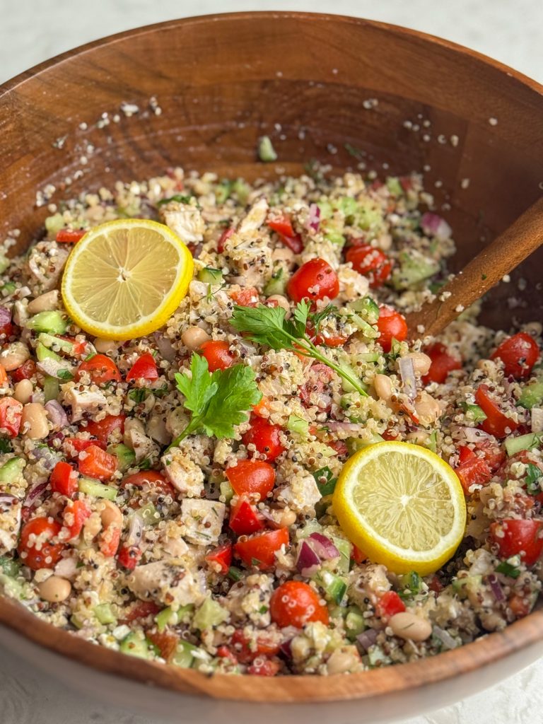 Mediterranean quinoa salad with fresh lemons and parsley in a large wooden bowl.