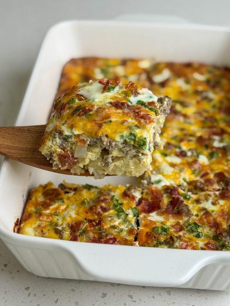 Easy prep ahead breakfast casserole recipe with wooden spatula holding a slice.