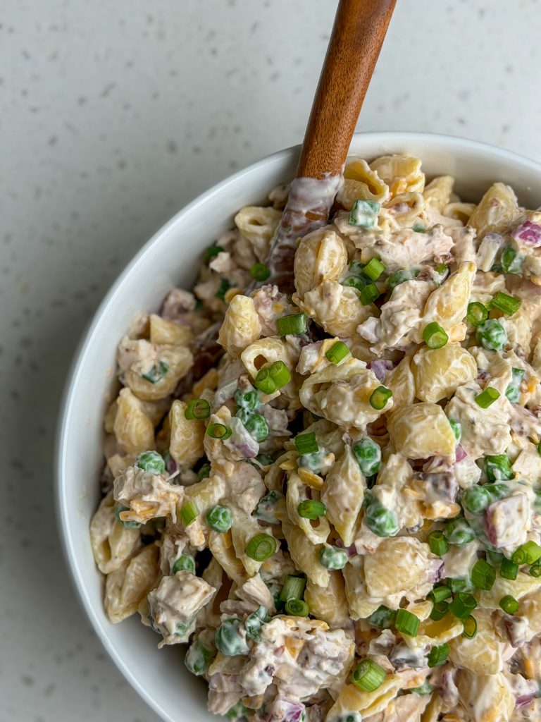 High protein chicken bacon ranch pasta salad with green onion in a white bowl.
