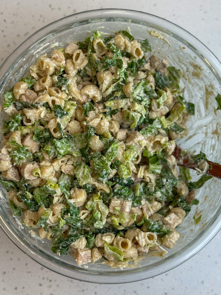 Healthy cottage cheese caesar pasta salad with noodles, chicken, and romaine lettuce in a glass bowl.