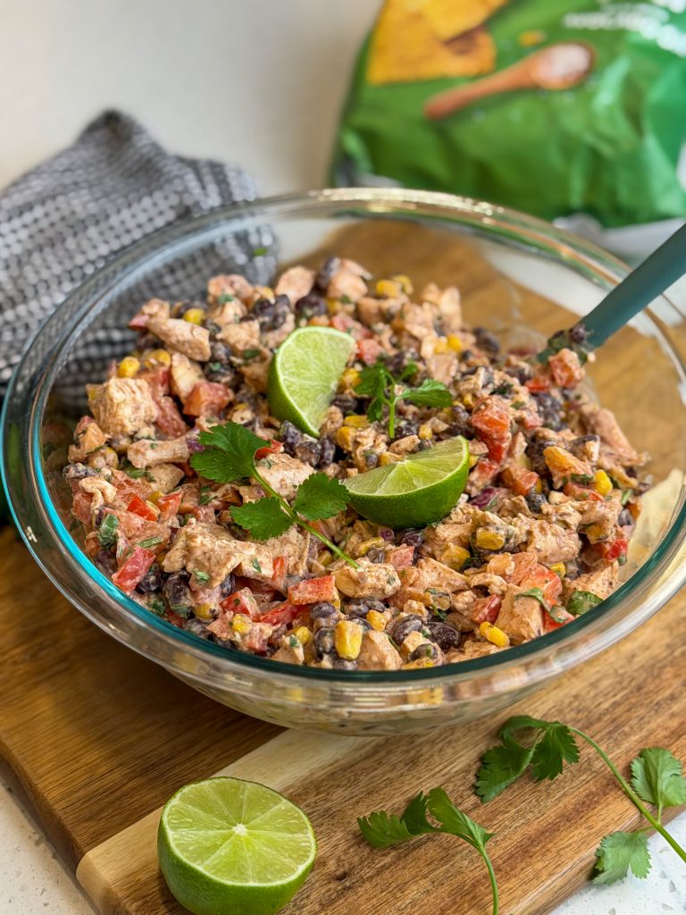 Southwest chicken salad in a glass bowl with fresh limes and cilantro.